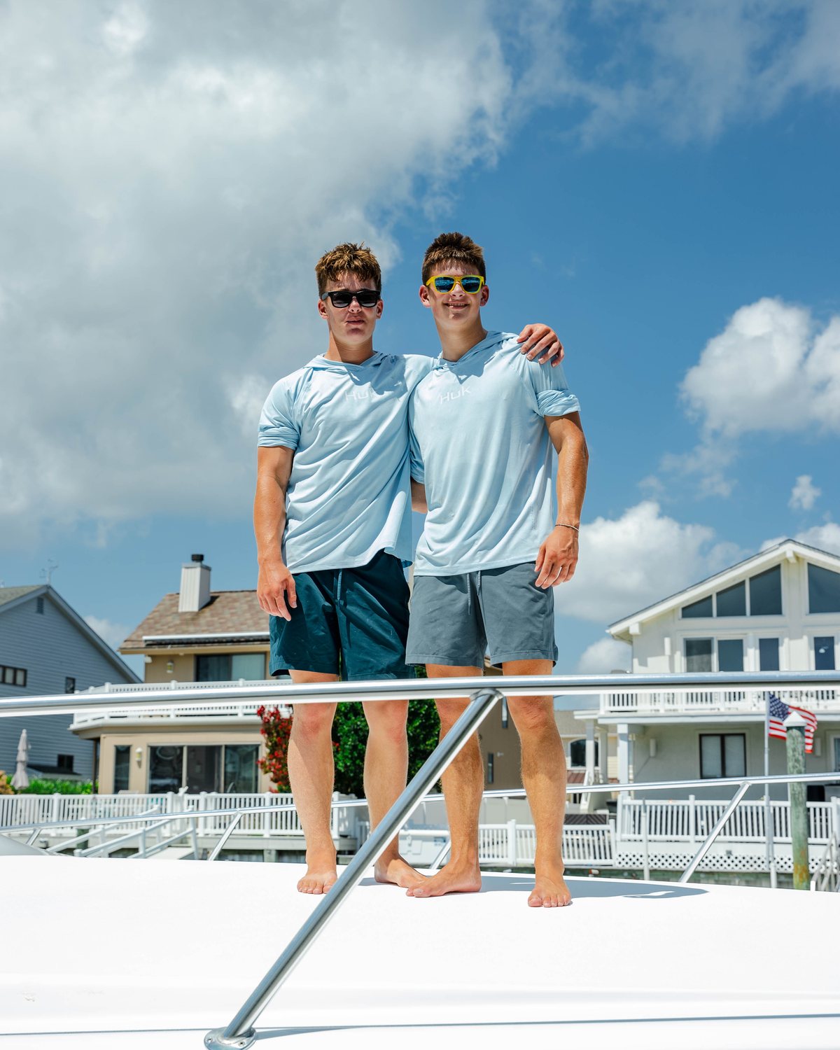 Two men standing together on the bow of a sportfish at a private dock, the boat finished behind them.